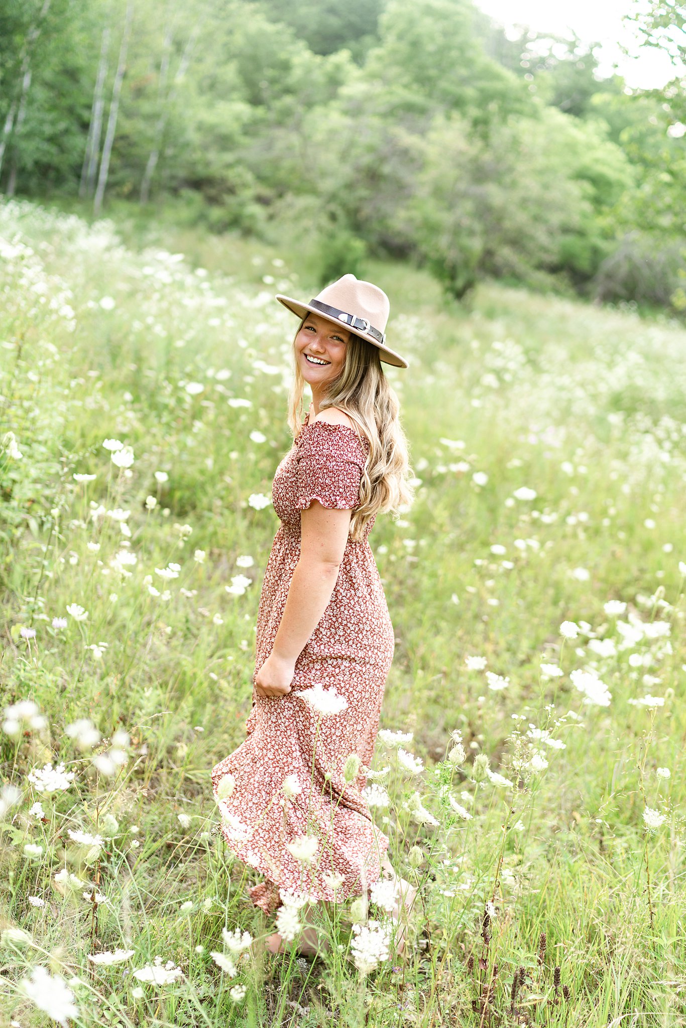 high school senior in pink dress and hat standing in a field of flowers Boutiques La Crosse WI