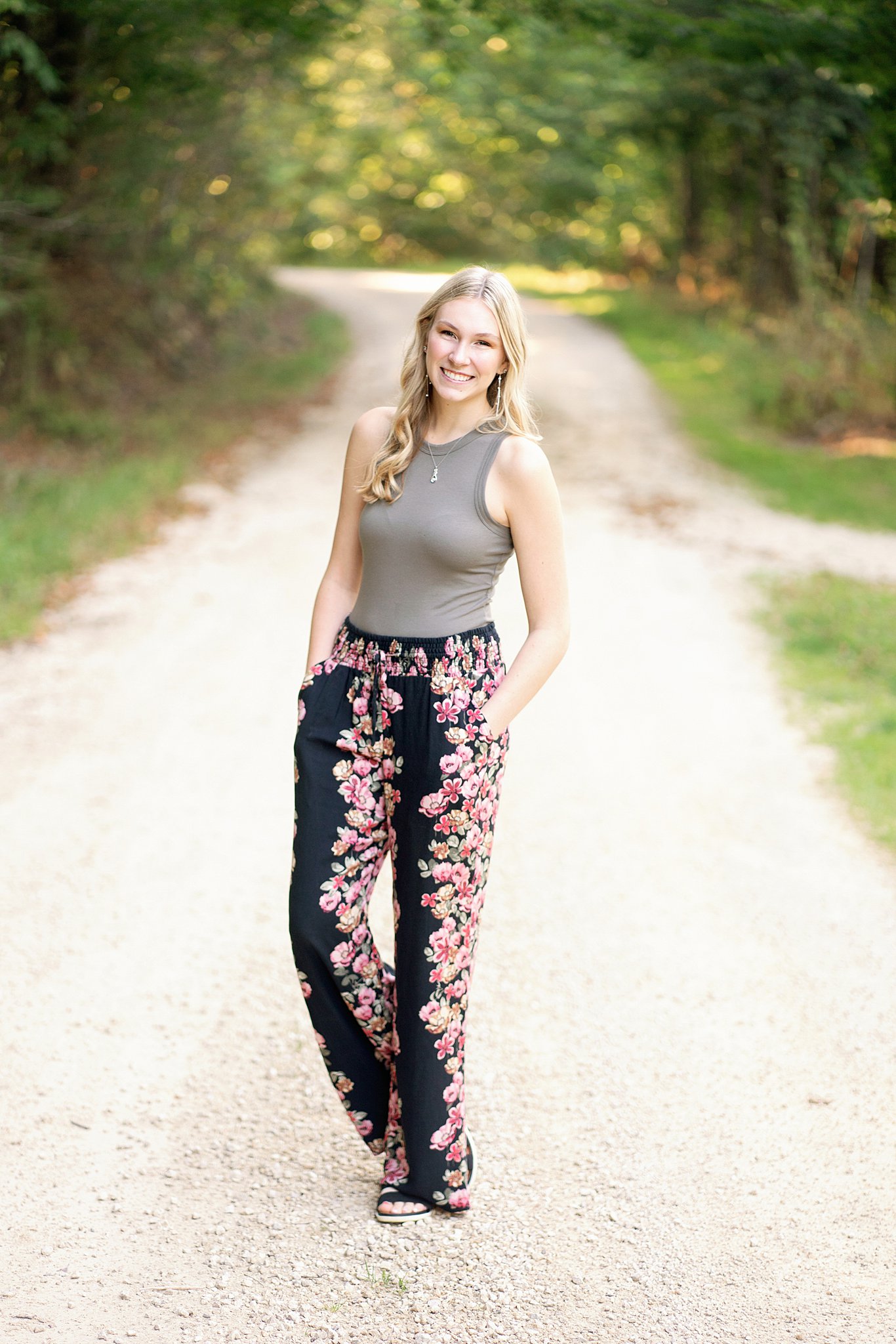 high school senior in grey top and floral pants from clothing boutiques in Rochester MN standing in the road