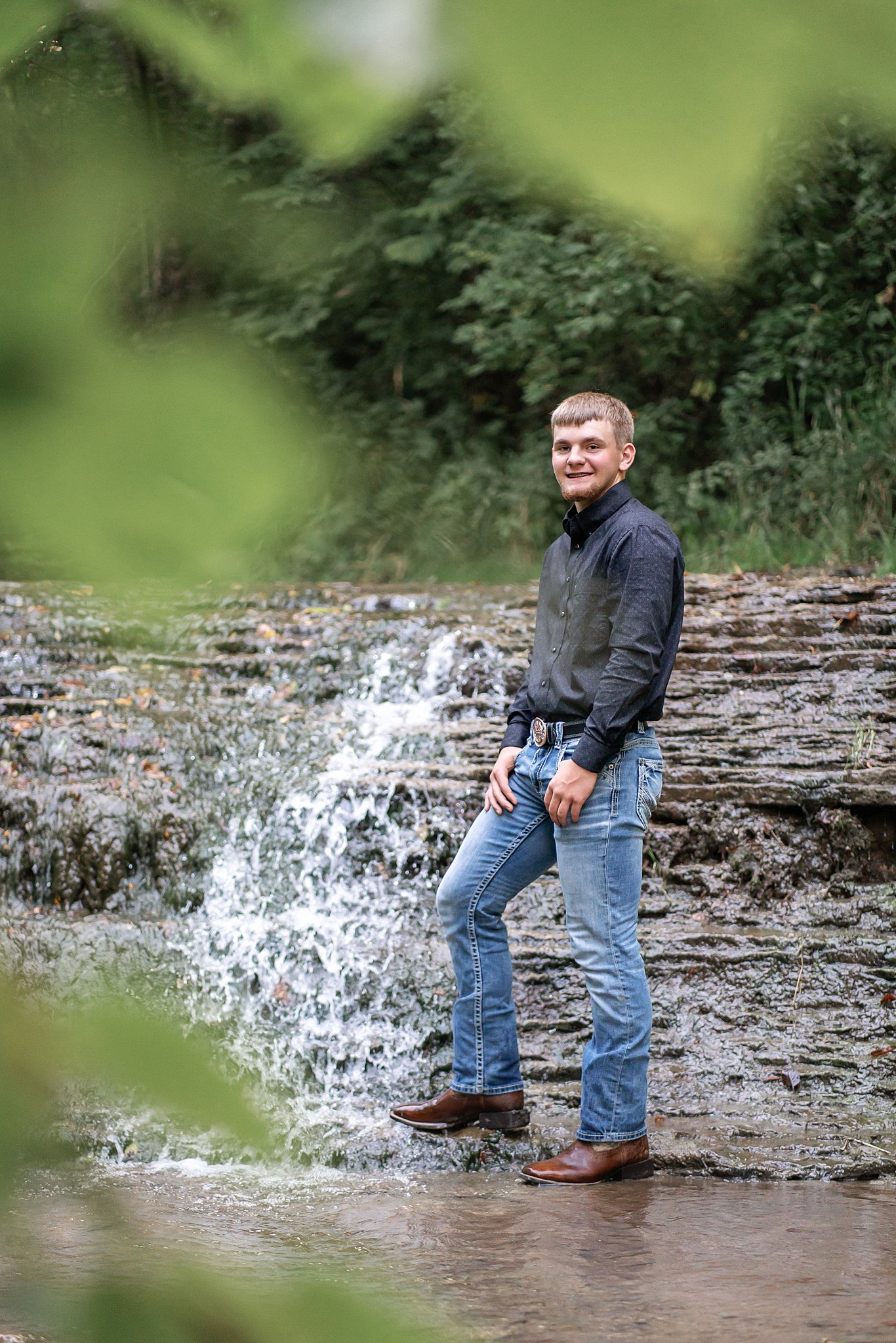 Rushford Peterson High School Senior in grey sweatshirt and jeans standing in the stream