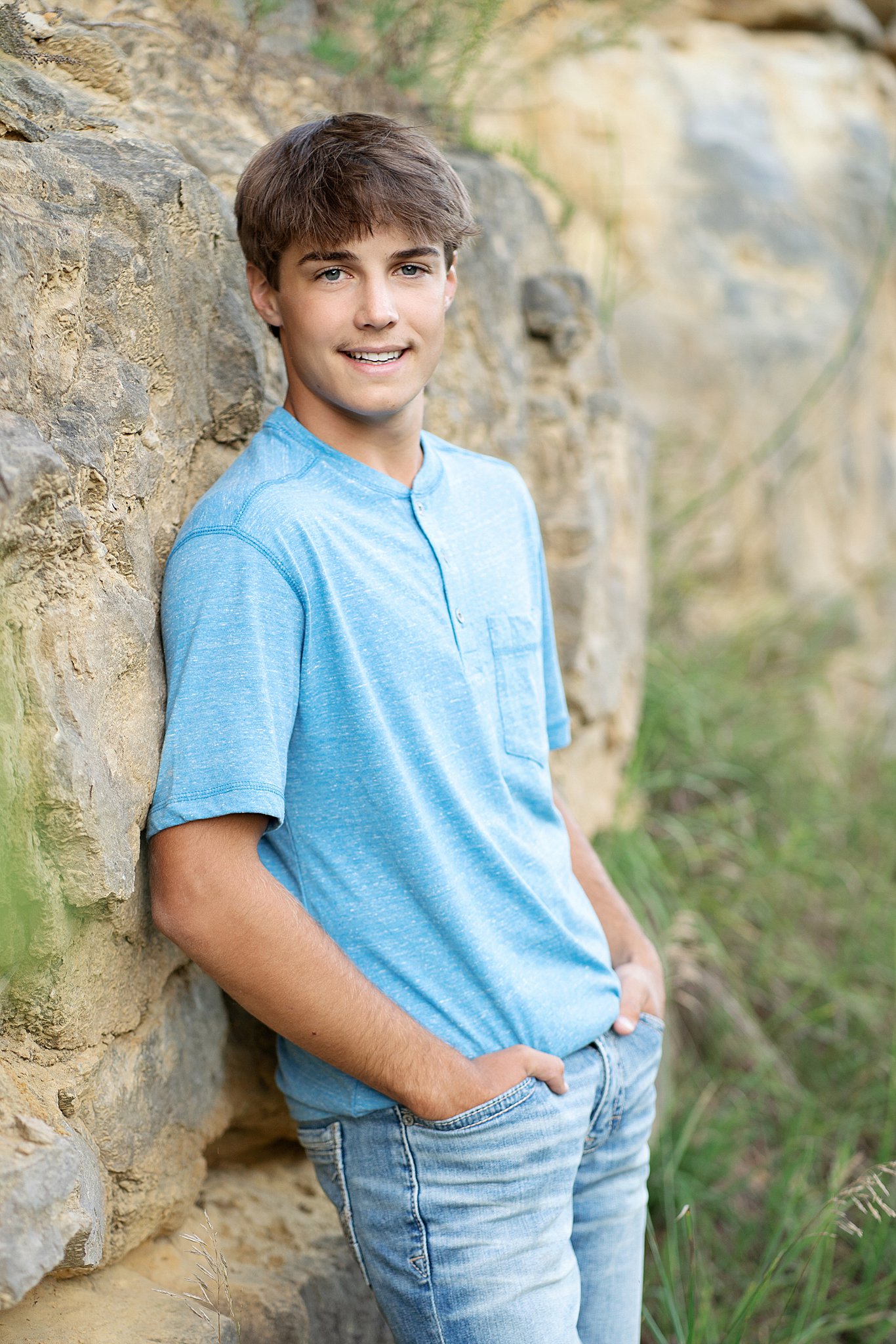 high school senior in a blue shirt leaning against a rock wall Tutors Rochester MN