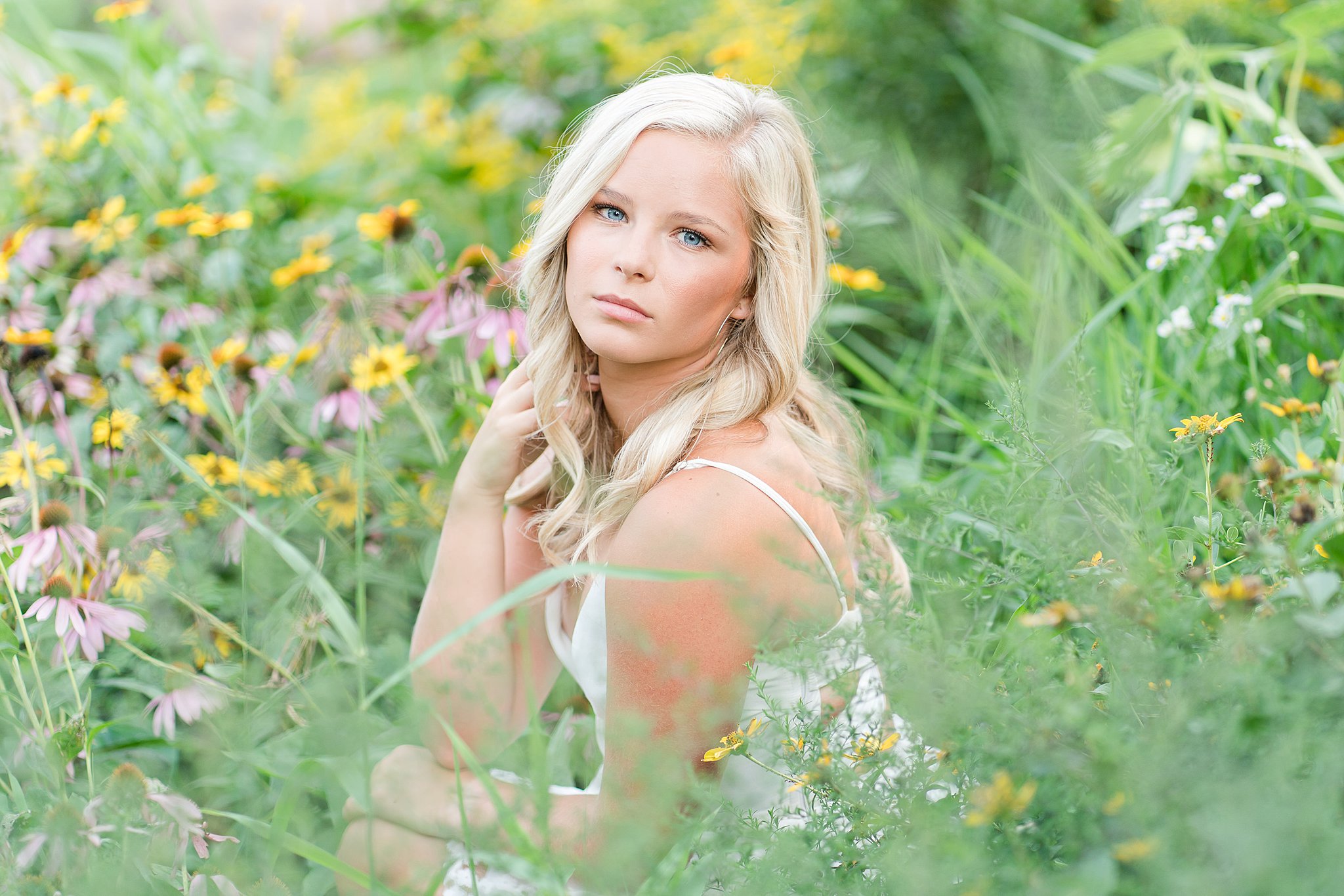 High school senior sits in a field of colorful wildflowers