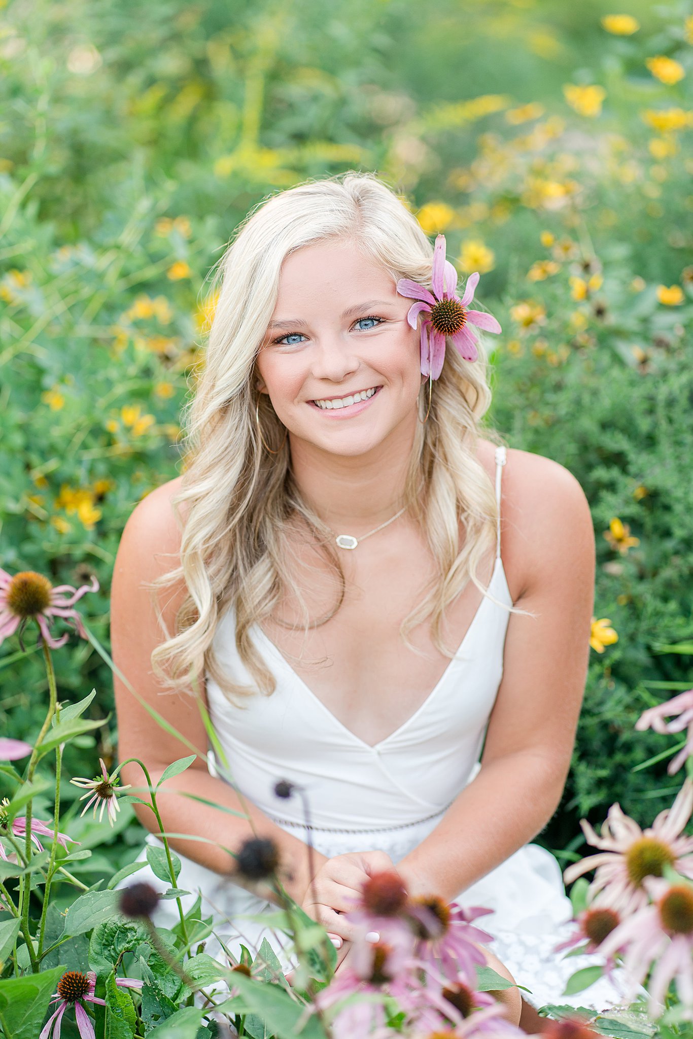 High school senior sits in a field of colorful wildflowers in a white dress Century senior high school