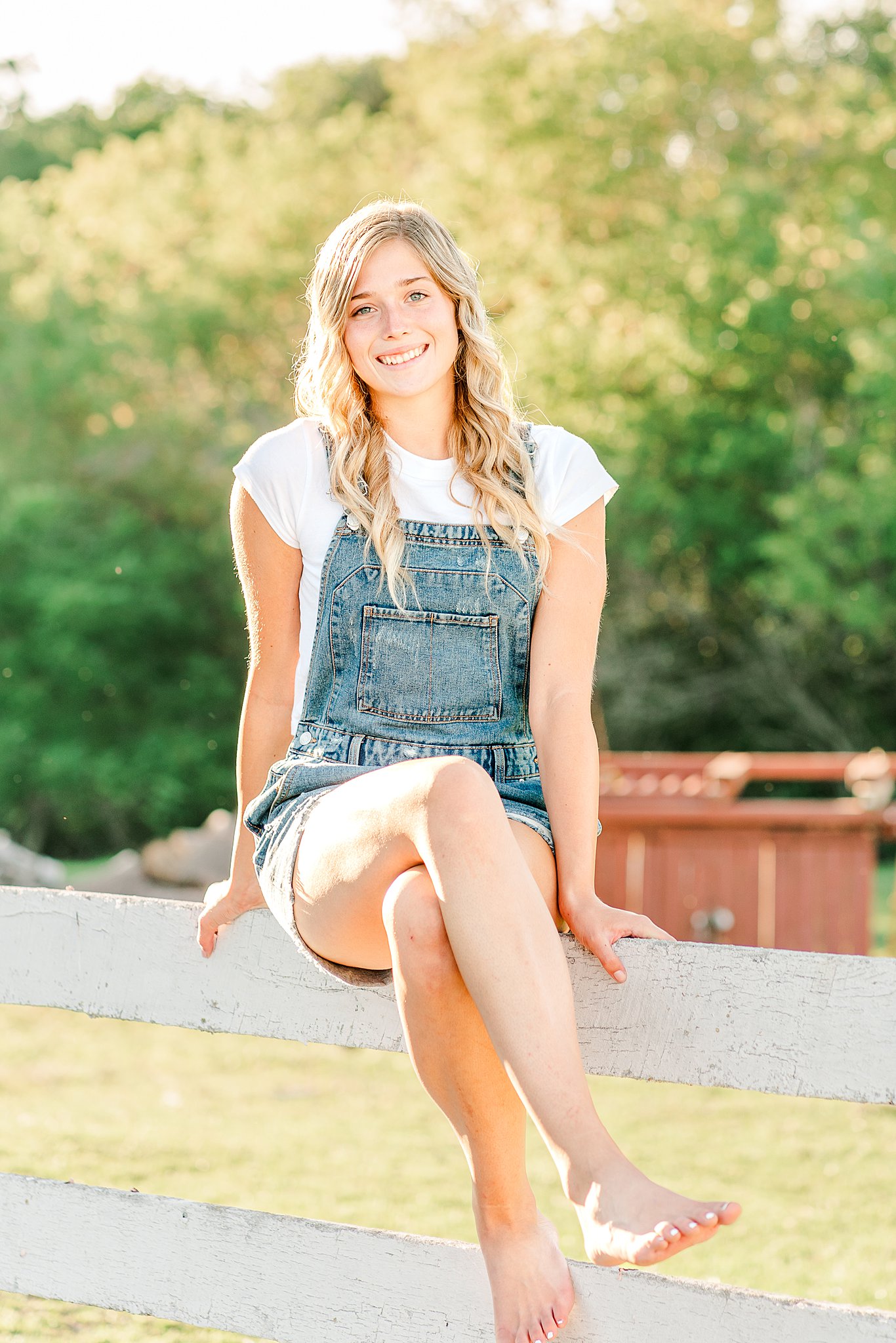 barefoot girl in overalls sits on a farm fence Hair salons rochester mn