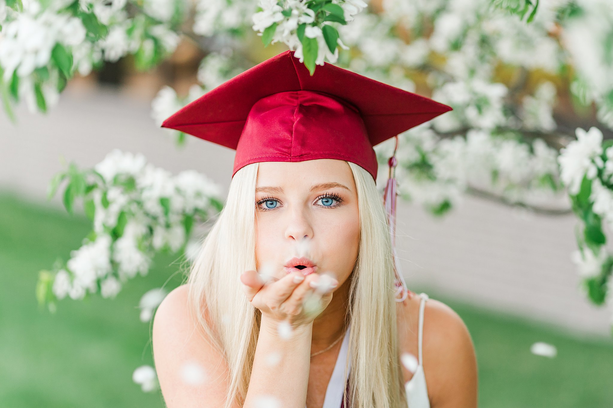 girl wearing graduation cap blows flowers in front of her act prep rochester MN
