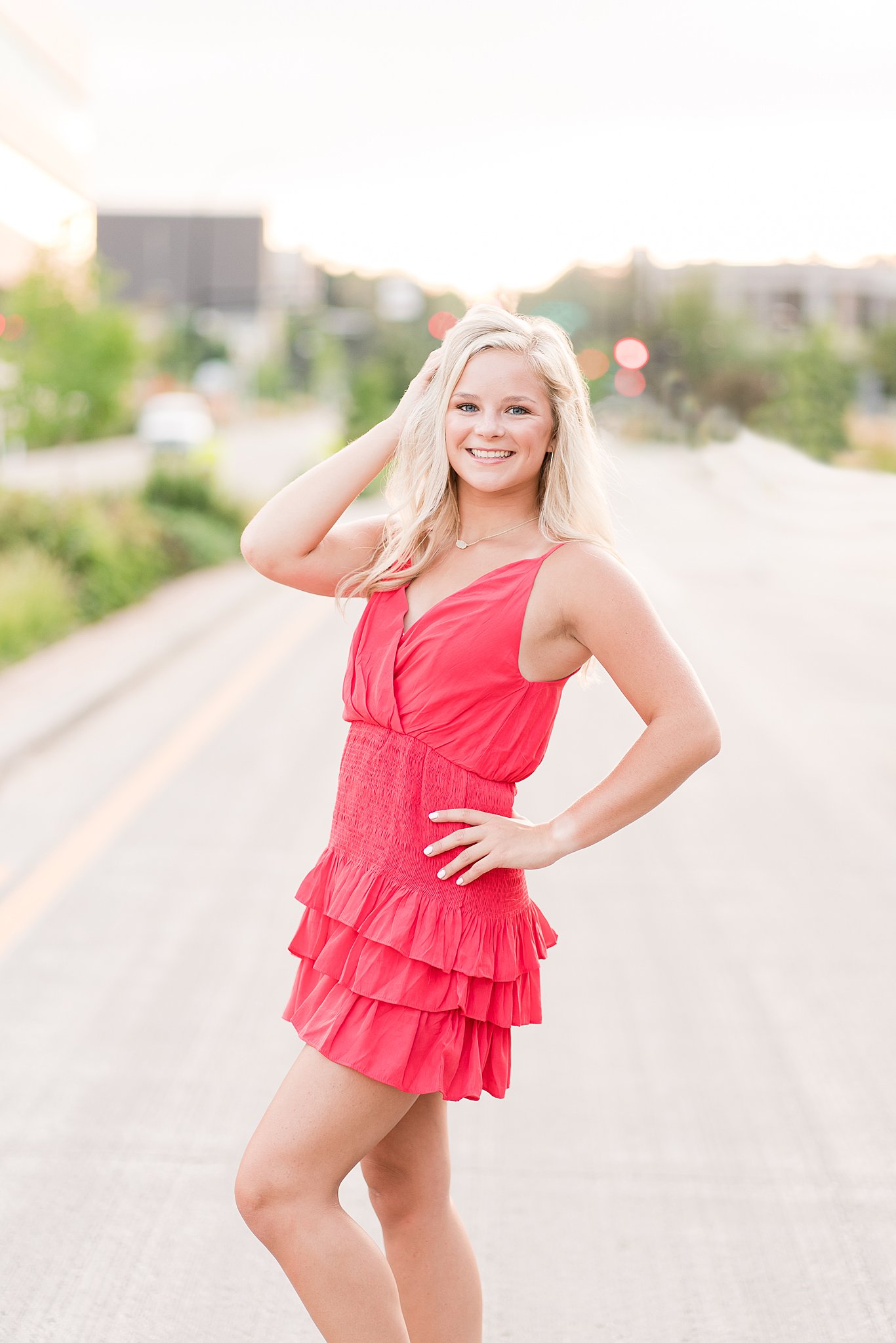 high school senior holds her hair and hip in a red dress in the middle of the road homecoming dresses rochester mn